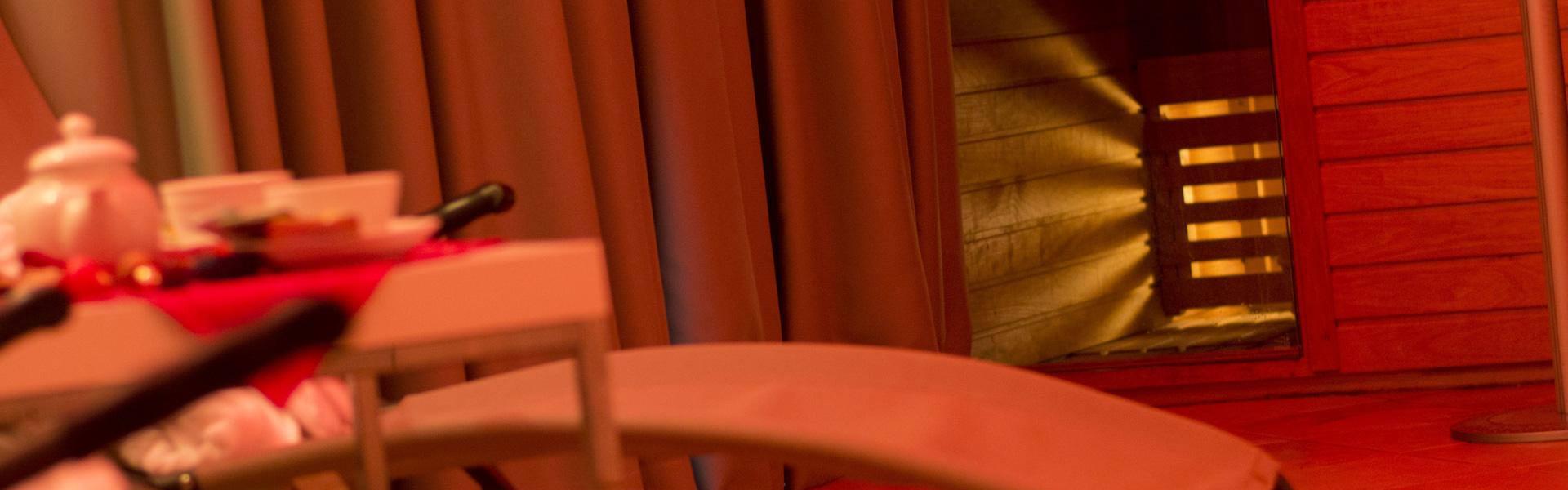 Sala relax con sedie a sdraio e tavolo, sauna sullo sfondo.