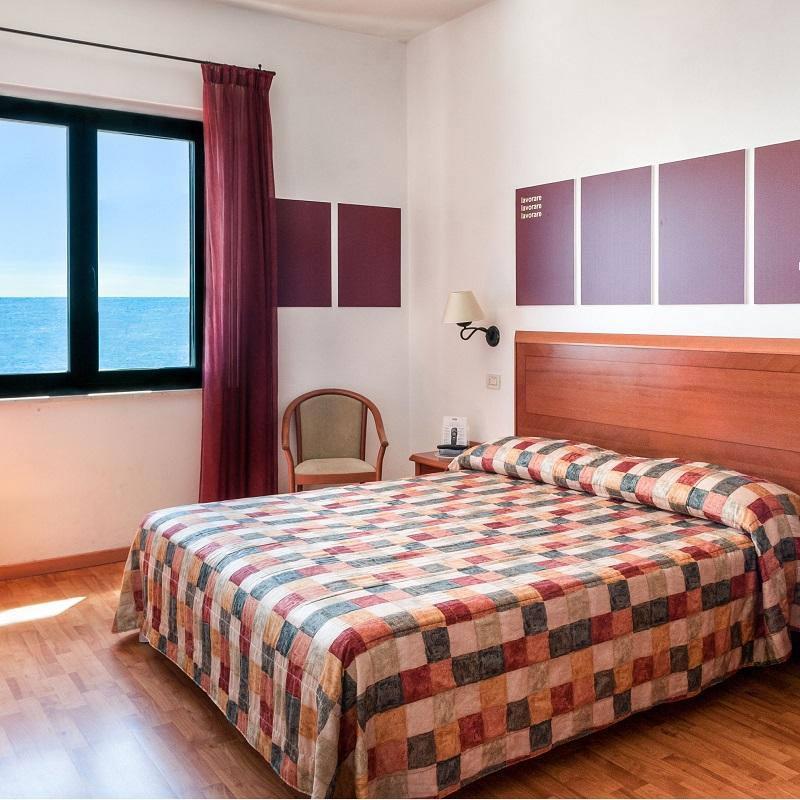 Camera con vista mare, letto matrimoniale e arredamento semplice.