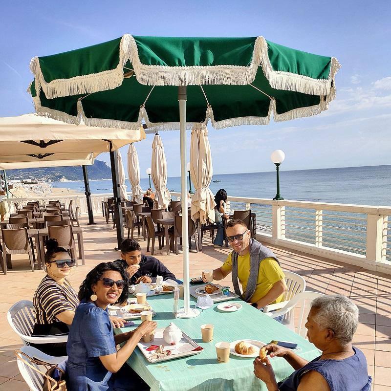 Famiglia che fa colazione all'aperto vicino al mare in una giornata soleggiata.